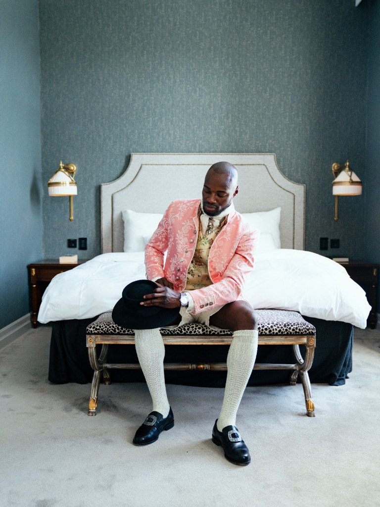 Color graded fullfigur av Lawrence med hatt i fanget foran seng
