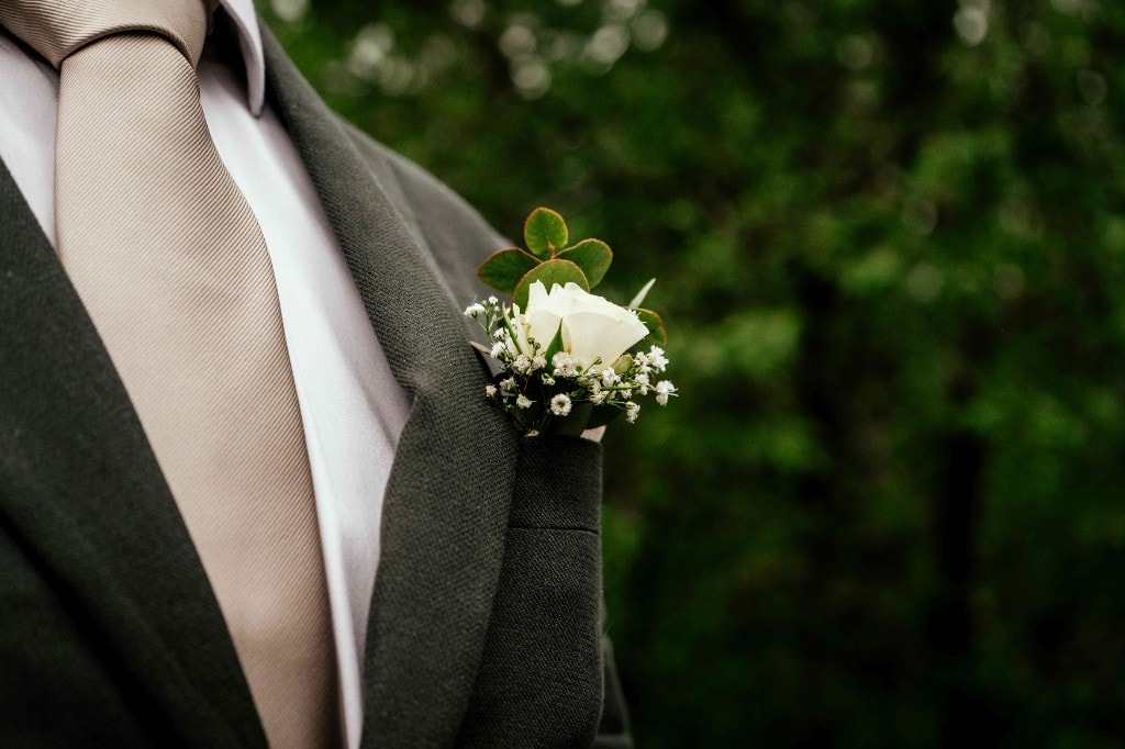 Detalj av brudgommens knapphullsblomst med hvit rose